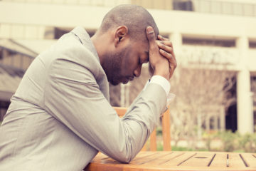 Man sitting at a table with head in his hands