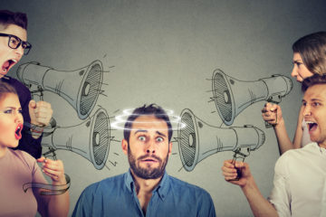 Man with stunned expression surrounded by people shouting through comic megaphones