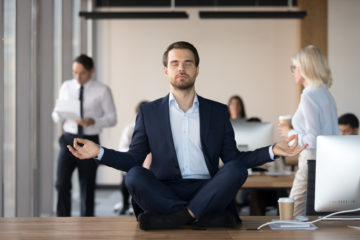 Man sitting cross-legged on a table in an office meditating